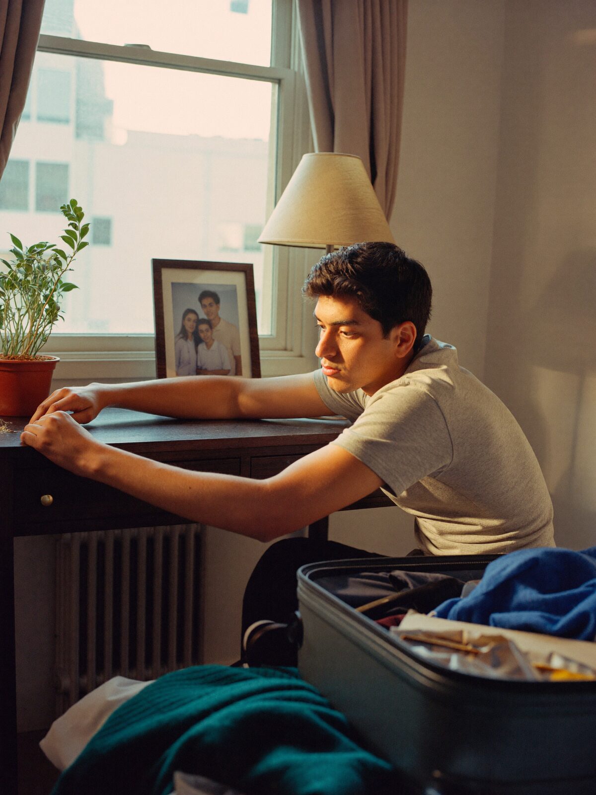A student unpacks on his first evening, placing a family photo on the desk.